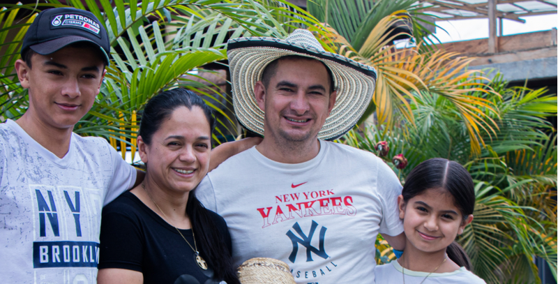 Family of five posing outdoors with tropical plants in the background