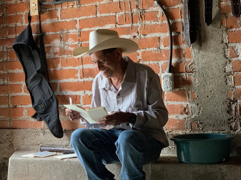 Farmer in a straw hat reading paperwork at the Las Terrazas mill